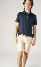 Man wearing stone Fletch 7.5-inch performance shorts with a navy polo
